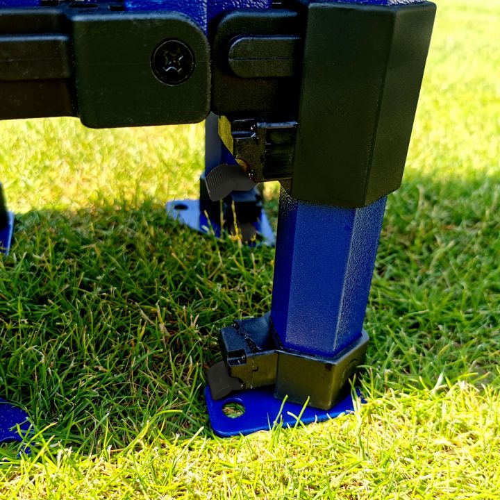 Detail of the lower part of the blue tent leg with a blue foot and a black sliding mechanism, standing on the grass.